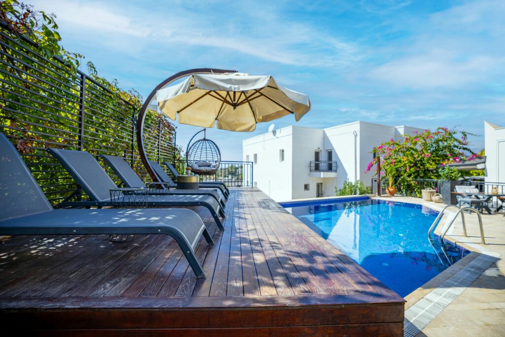 Relax at a luxurious Bodrum poolside with lounge chairs and umbrellas under a bright sky.